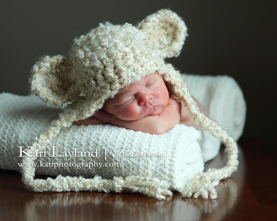 Newborn sleeping on her tummy wearing a crochet teddy bear hat