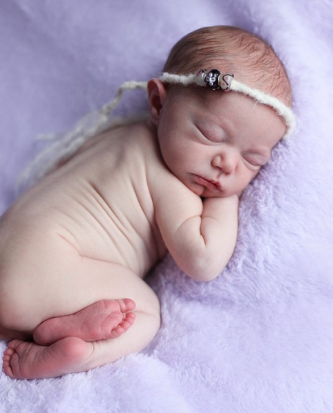 Newborn girl on purple blanket
