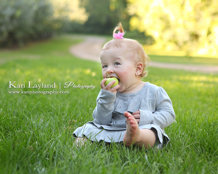 Baby girl eating an apple.  MN portrait photography by Kari Layland.