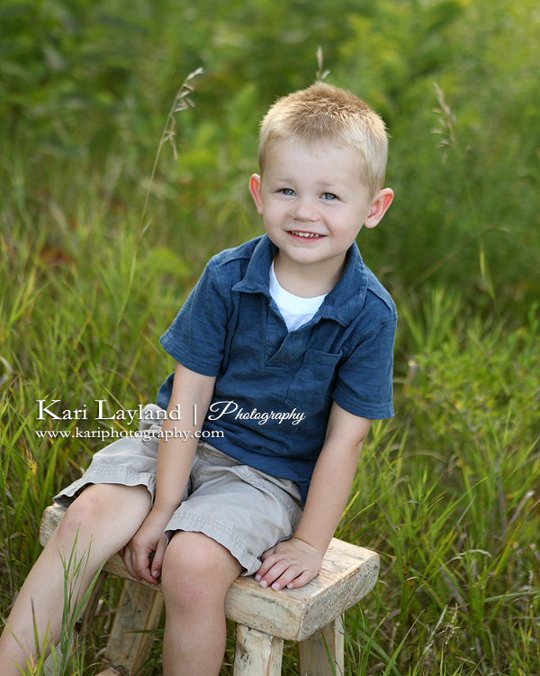 Cute little boy sitting on a stool in the long grass. Photography by Kari Layland.