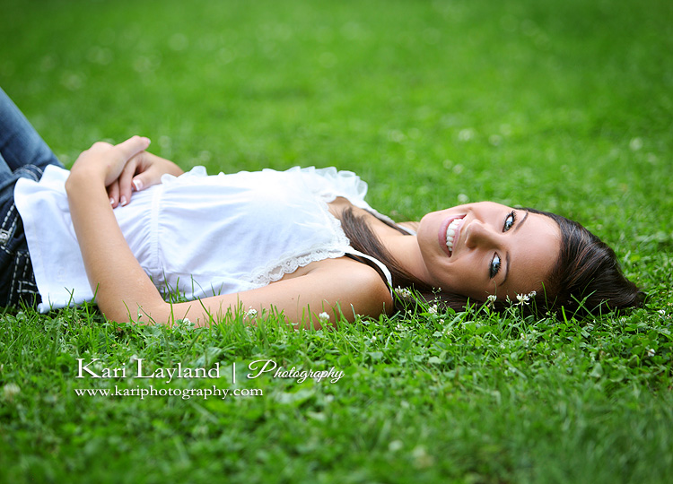 pretty senior portrait of a girl laying in the grass.  Taken by Kari Layland Photography.